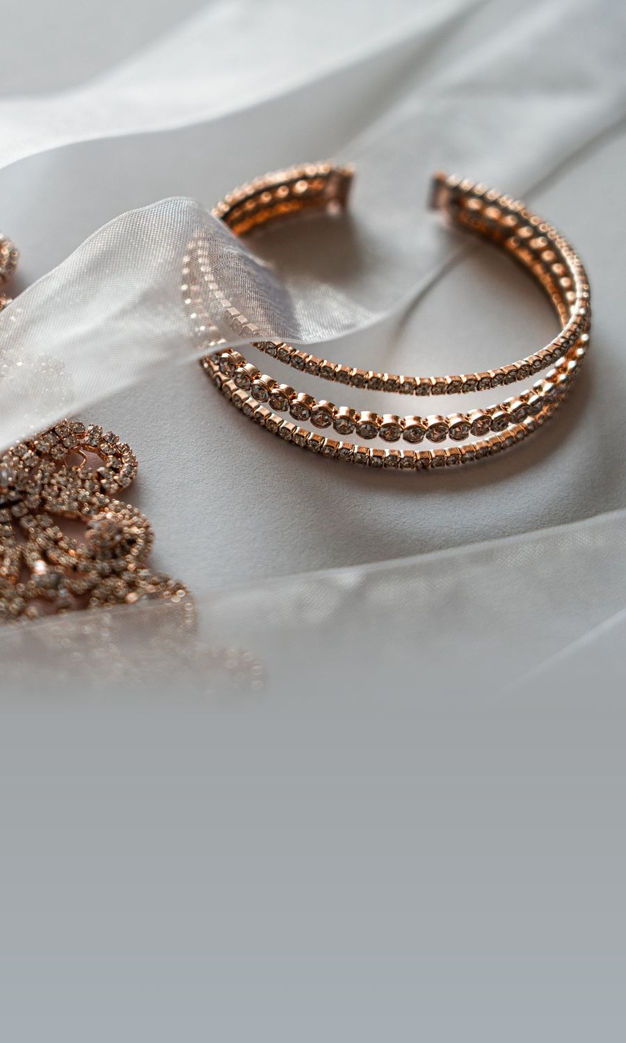 A rose-gold bangle resting on ivory organza