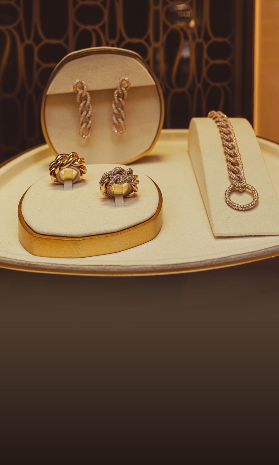 Gold rings, earrings and a bracelet on an ivory display in warm light